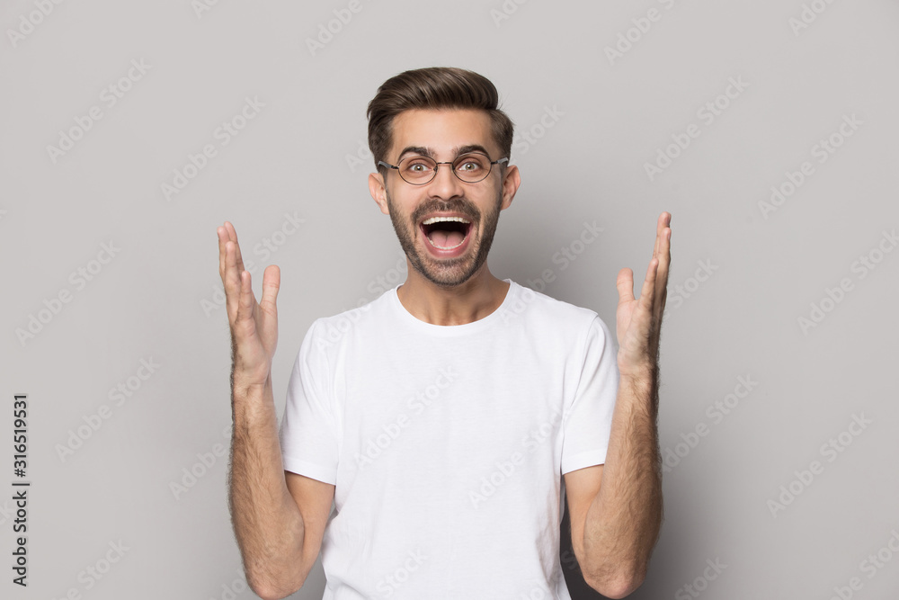 Fototapeta premium Cheerful young man in eyeglasses hearing unbelievable good news.