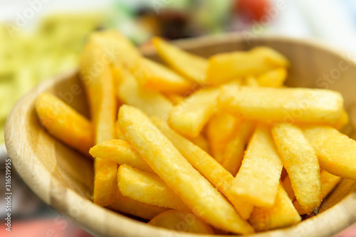 french fries with spice sauce in wooden bowl