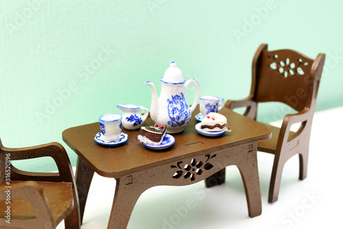  Toy brown wooden table with teapot  cups and saucers and two chairs