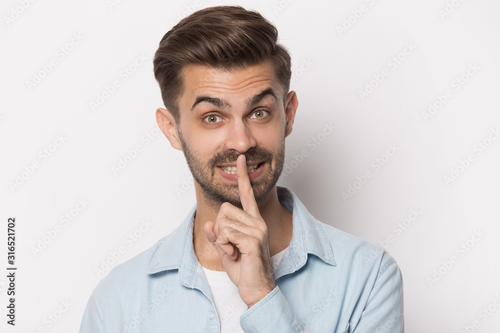 Handsome young man showing hush gesture portrait. Handsome young man showing hush gesture portrait.