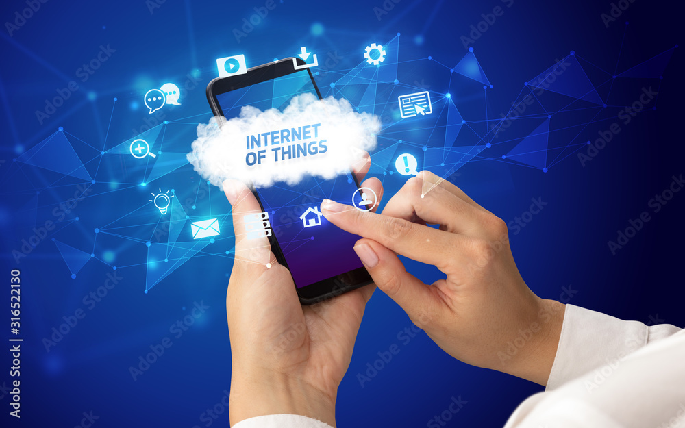 Female hand holding smartphone with INTERNET OF THINGS inscription, cloud technology concept Female hand holding smartphone with INTERNET OF THINGS inscription, cloud technology concept