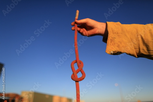 Rope access technician construction mine worker holding static 10.5 mm low stretch rope inspecting a figure of eight  knot prior to use tie on safety harness loop  