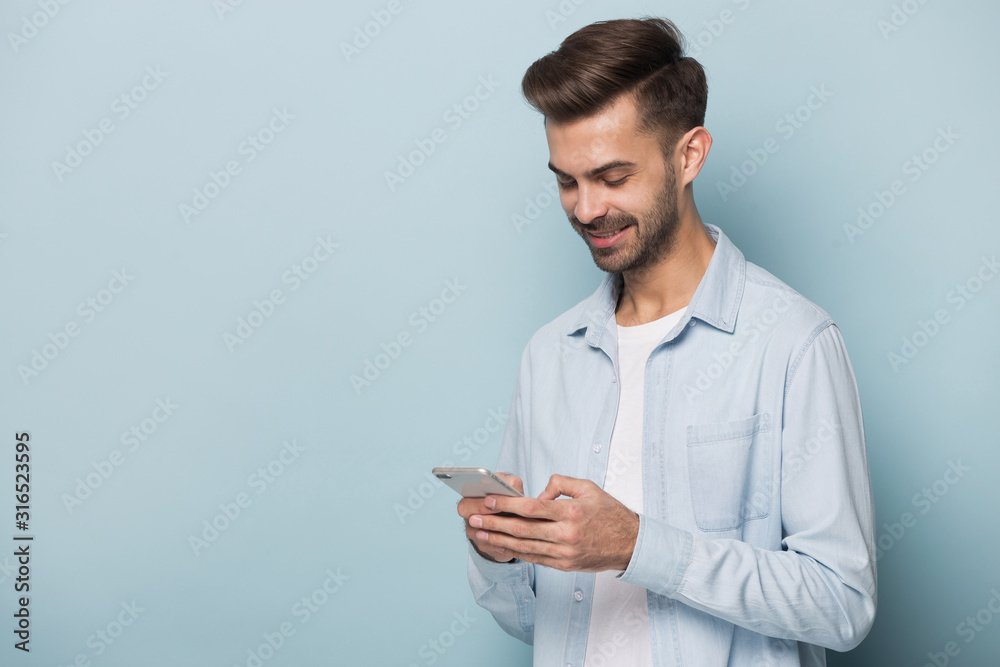 Smiling young man holding mobile phone, standing aside copy space. Smiling young man holding mobile phone, standing aside copy space.