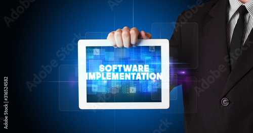 Wallpaper Mural Young business person working on tablet and shows the inscription: SOFTWARE IMPLEMENTATION Torontodigital.ca