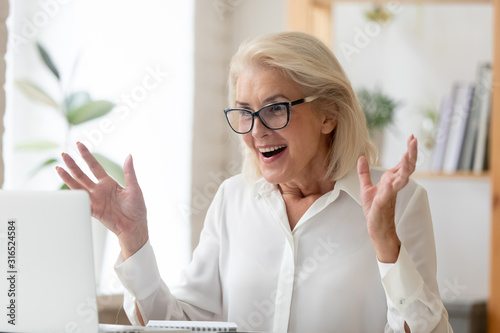 Middle-aged businesswoman feeling amazement received unbelievable online news photo