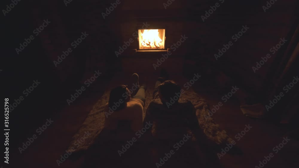 The young couple sitting on the floor by the fireplace The young couple sitting on the floor by the fireplace