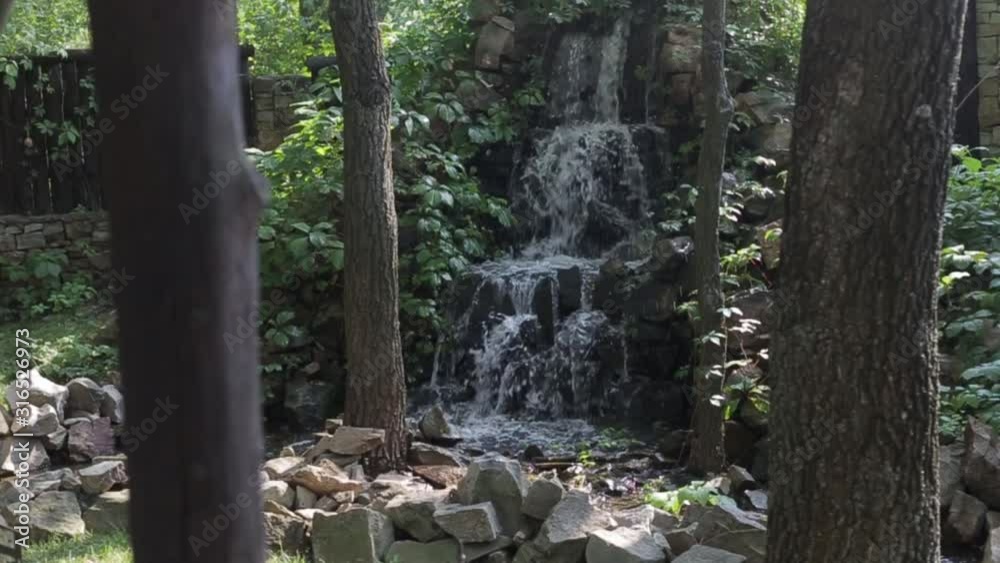 small artificial waterfall among trees and bushes small artificial waterfall among trees and bushes