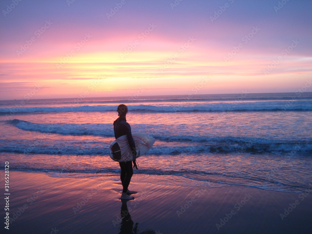 surfer looking out at the sea and a colourful sunset in africa/morocco