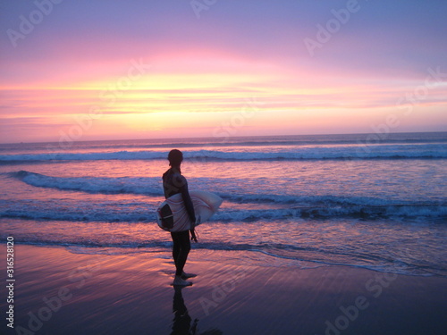 surfer looking out at the sea and a colourful sunset in africa morocco