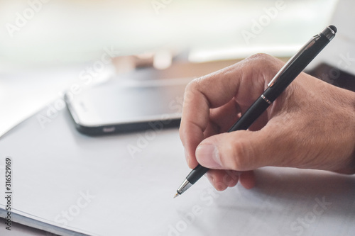 Businessman holding pen writing on paper document working,Close up hand write paperwork