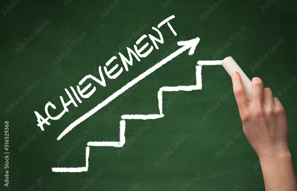 Hand drawing ACHIEVEMENT inscription with white chalk on blackboard, business concept
