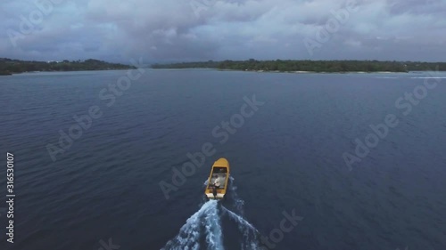 Tracking Aerial Of Motorboat Sailing on Calm Tropical Sea Toward Exotic Island in Twilight photo