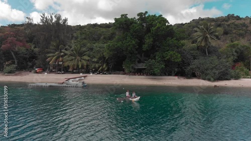 Couple Paddling on Boat and Sailing Offcoast From Exotic Island In Tropical Sea, Drone Aerial View photo