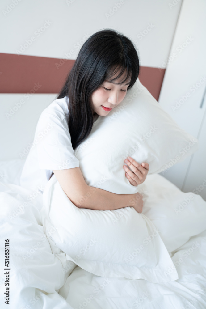 young woman holding pillow on the bed at home young woman holding pillow on the bed at home