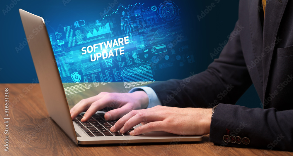 Businessman working on laptop with SOFTWARE UPDATE inscription, cyber technology concept Businessman working on laptop with SOFTWARE UPDATE inscription, cyber technology concept