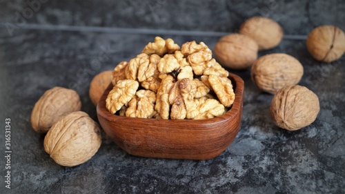walnut kernels in a wooden dish on a black background