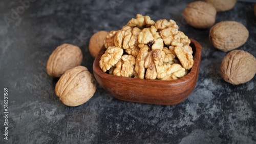 walnut kernels in a wooden dish on a black background