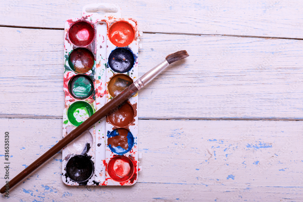 Professional watercolor aquarell paints in box with brushes on old white wooden board Professional watercolor aquarell paints in box with brushes on old white wooden board