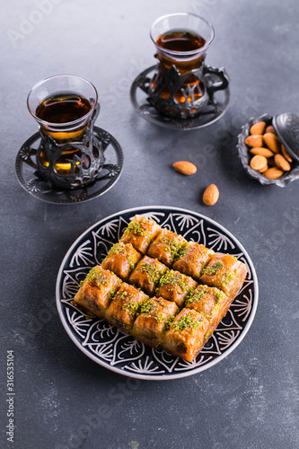 Baklava. Ramadan Dessert. Traditional Arabic dessert with nuts and honey, two cups of tea on a concrete table.