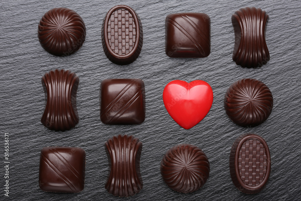 Red heart and chocolate candies on black slate stone. Valentines day greeting card. Red heart and chocolate candies on black slate stone. Valentines day greeting card.
