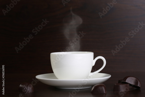 Cup of coffee and chocolate candies on wooden background