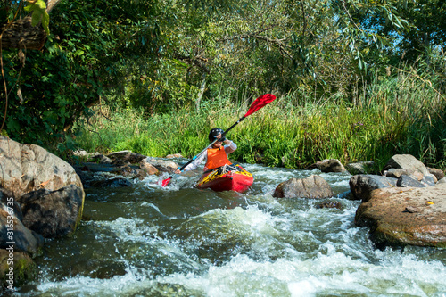 sport woman in the helmet on the kayak in the river with white water
