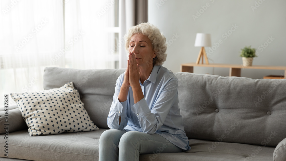 Older woman praying with hope at home, holding hands together Older woman praying with hope at home, holding hands together