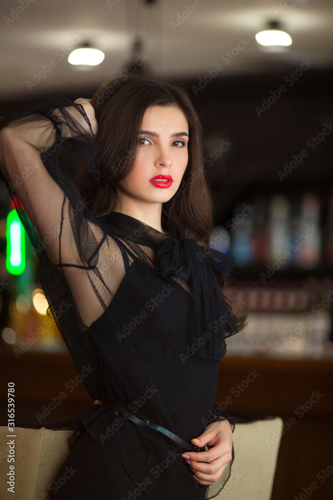 portrait of a beautiful young woman in a black dress indoors