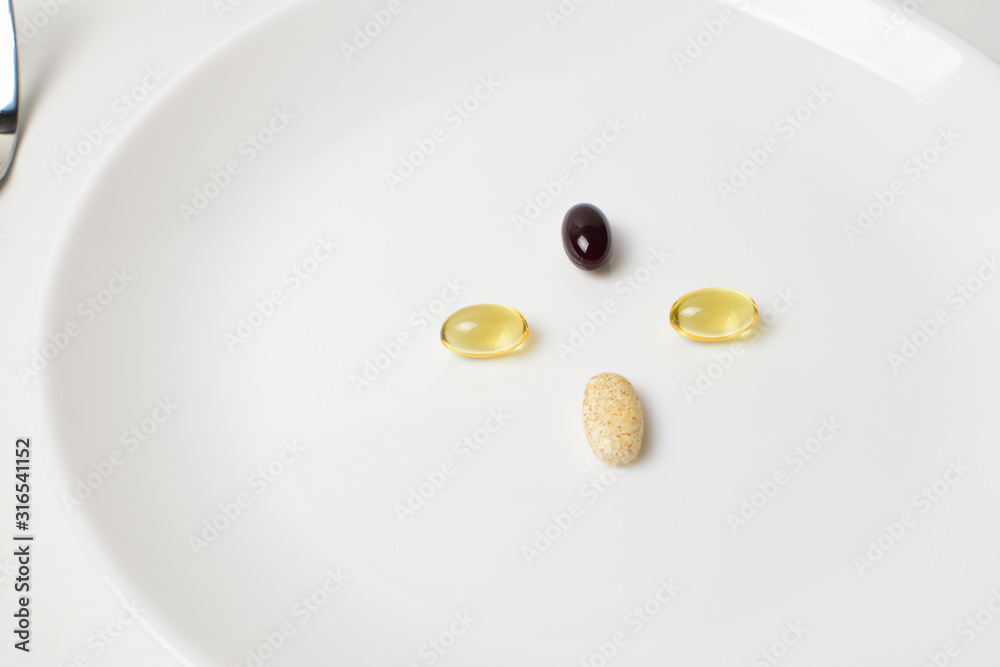 Multivitamin and mineral diet supplements. Astaxanthin. Plate with tablets. Meal replacement. Closeup. Multivitamin and mineral diet supplements. Astaxanthin. Plate with tablets. Meal replacement. Closeup.