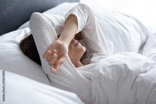 Sleepless young woman suffering from insomnia, covering eyes with hands photo