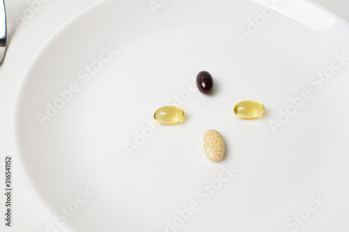Multivitamin and mineral diet supplements. Astaxanthin. Plate with tablets. Meal replacement. Closeup.