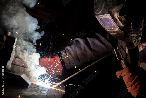 worker welds metal structures by electric arc welding