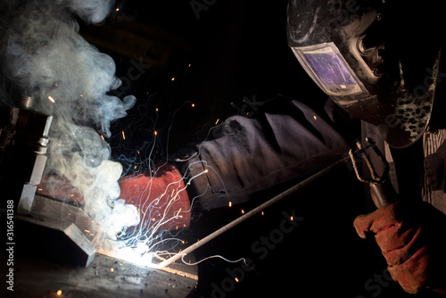 worker welds metal structures by electric arc welding photo