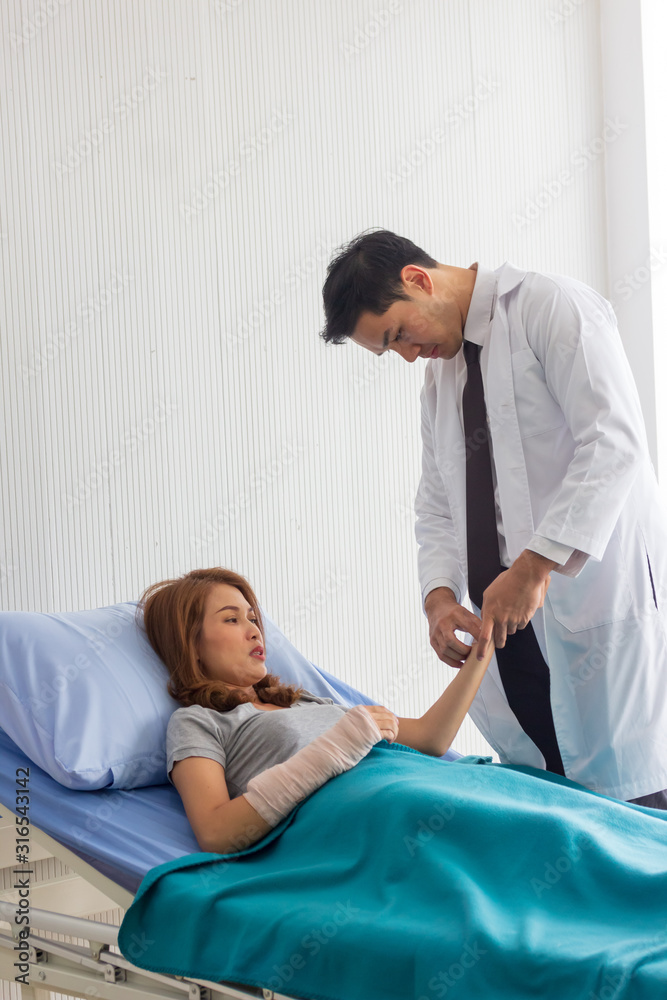 Fototapeta premium Male Asian doctor checked the patient's pulse to check the abnormalities of the heart in the bed.