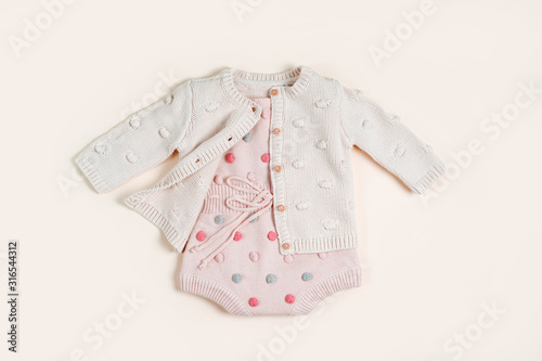 Pastel knitted romper with dots and cute jumper. Fashion newborn clothes. Flat lay, top view