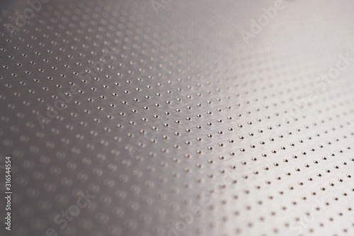 Aluminum surface with many notch spots. Abstract dark gray metallic background or wallpaper. Rows of points go into the distance and form a perspective. Macro