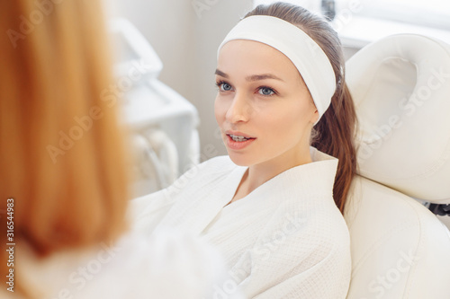 Young pretty woman came to a beauty salon and consults with a beautician on anti-aging treatments. Self care concept. The patient and the doctor. Clinic of modern medicine, the diagnosis of disease