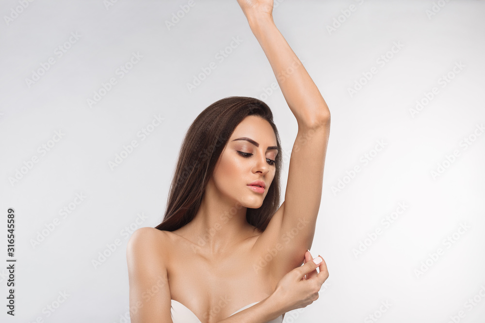 Fototapeta premium Armpit epilation, lacer hair removal. Young woman holding her arms up and showing clean underarms, depilation smooth clear skin .Beauty portrait. Copyspace