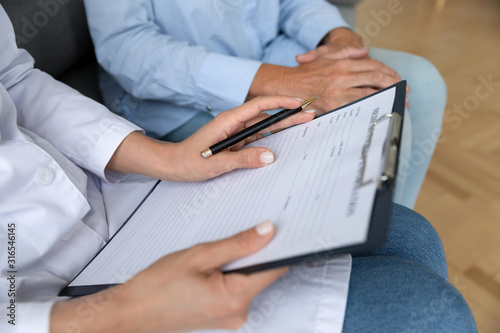 Close up doctor holding clipboard with older patient documents