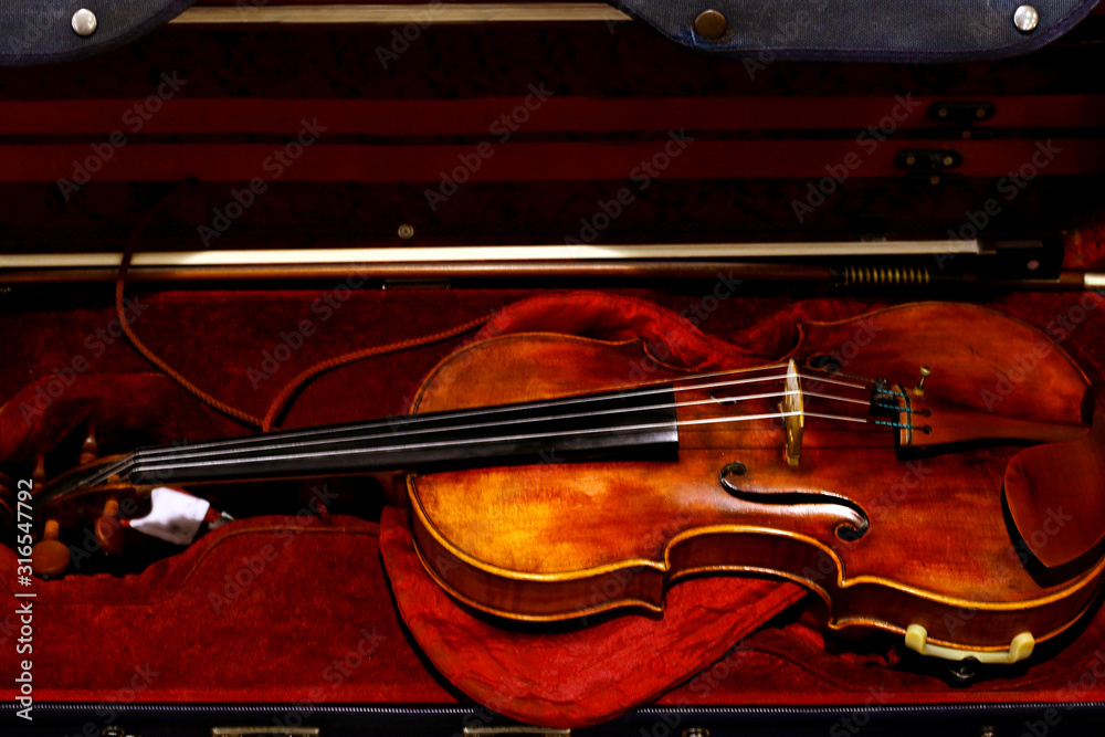 Fototapeta premium Violin in red velvet case. Classical wooden Violin in open red case. Top view. 