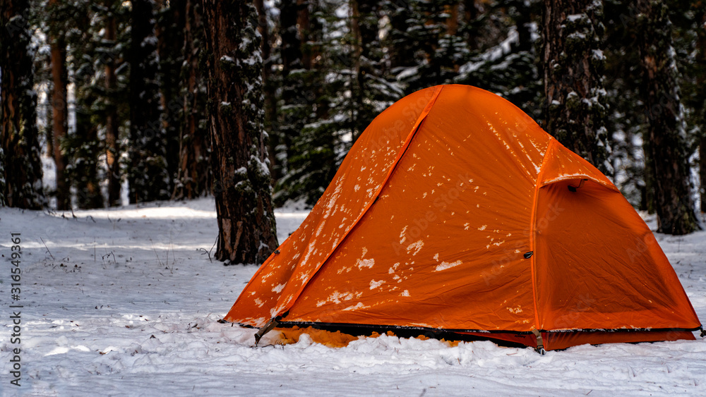 orange camping tent in snowy forest