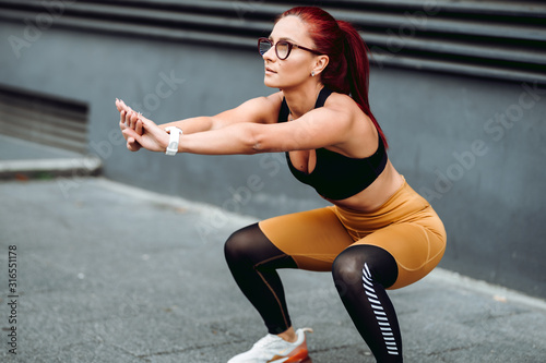 portrait of female woman doing squats training. Muscular woman doing cross fit workout outdoors © aboutmomentsimages
