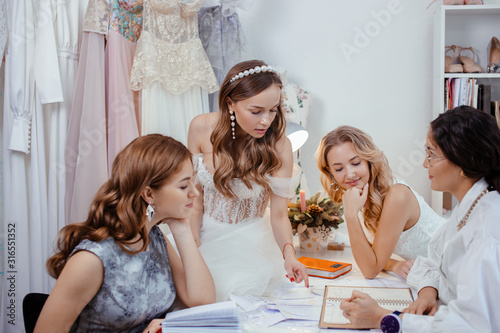 group caucasian models have conversation with designer and tailor of wedding dresses  have friendly conversation and consultation or advice  which style and type of dress is appropriate and for whom