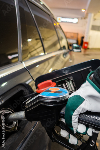 Fueling up a car with diesel at a service station with gloves on
