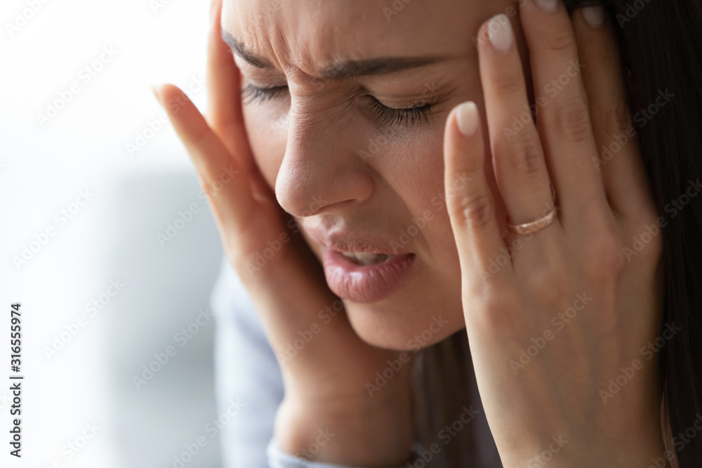 Close up unhappy pressured woman suffering from strong headache Close up unhappy pressured woman suffering from strong headache