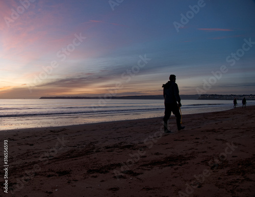 dog walkers on the beach at dawn