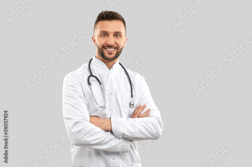 Smiling doctor with strethoscope isolated on grey. © serhiibobyk