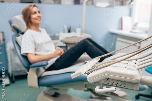 side view on young caucasian woman sitting in dental office wearing casual clothes  waiting for doctor  for medical check-up  teeth exam by professional doctor
