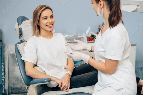 friendly dentist woman treating beautiful patient in dental office, doctor in white uniform, professional orthodontist