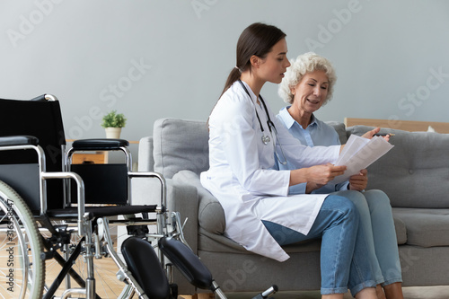 Doctor consulting disabled older woman about checkup result at home